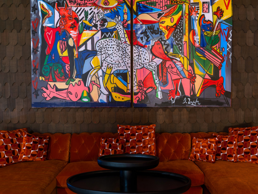 Custom velvet furniture and pillows crafted from fabrics by Guell underneath two large paintings by Domingo Zapata.