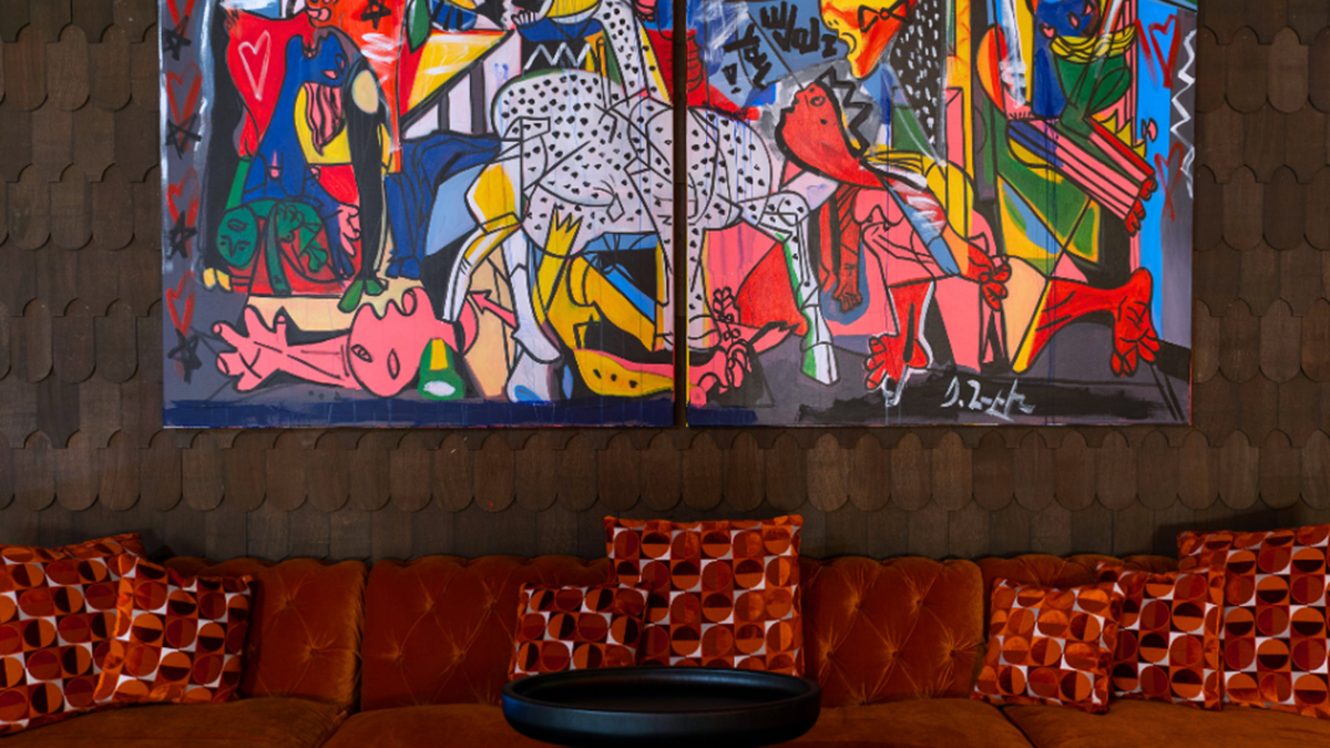 Custom velvet furniture and pillows crafted from fabrics by Guell underneath two large paintings by Domingo Zapata.